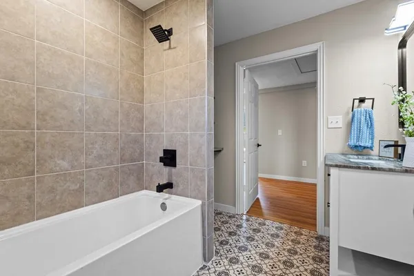 a bathroom with a tub a sink and a mirror