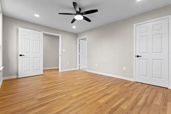 a view of empty room with wooden floor and fan