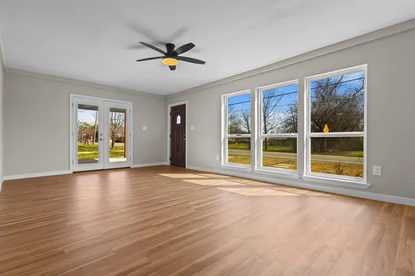 a view of an empty room with a window and wooden floor