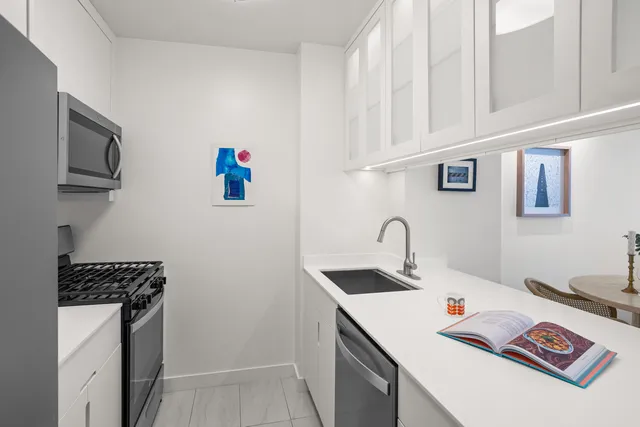 a living room with stainless steel appliances a kitchen island hardwood floor sink and window