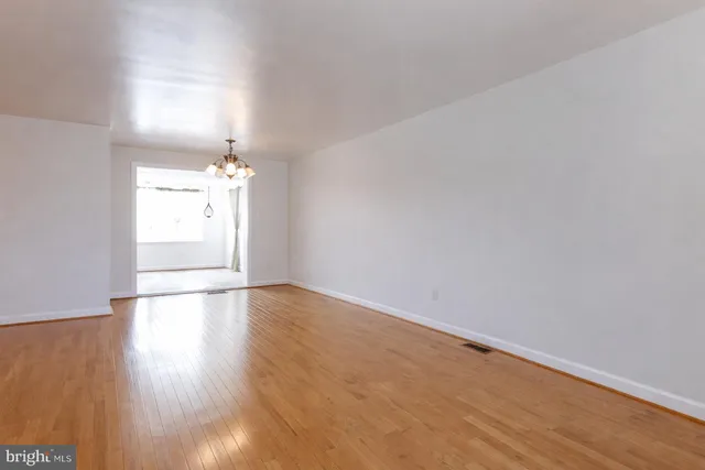 an empty room with wooden floor and chandelier