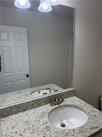 a bathroom with a granite countertop sink and a mirror