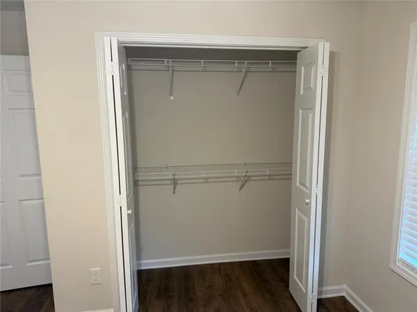 an empty room with wooden floor fan and window