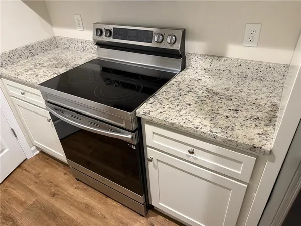 a kitchen with granite countertop white cabinets and a stove