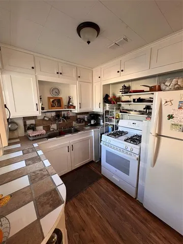 a kitchen with granite countertop a stove a sink and a refrigerator