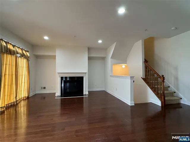 an empty room with wooden floor fireplace and windows