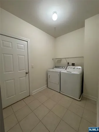 a view of an empty room with wooden floor and a kitchen