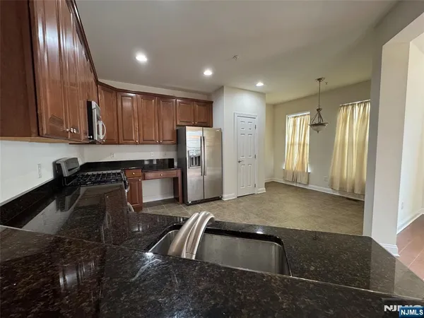 a kitchen with granite countertop stainless steel appliances a sink stove and cabinets