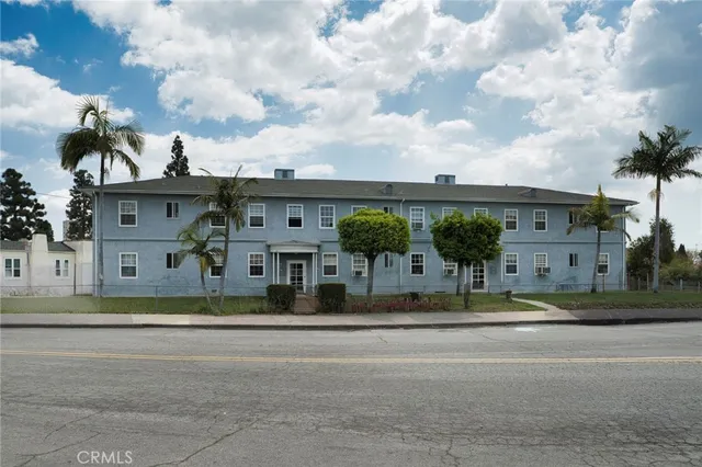 a front view of a house with a garden and trees