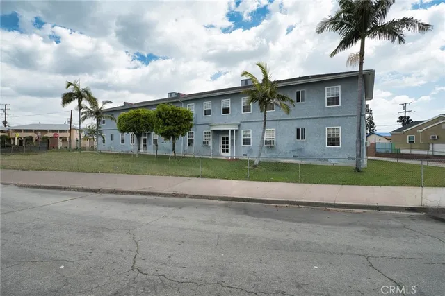 a view of a house with a big yard and palm trees