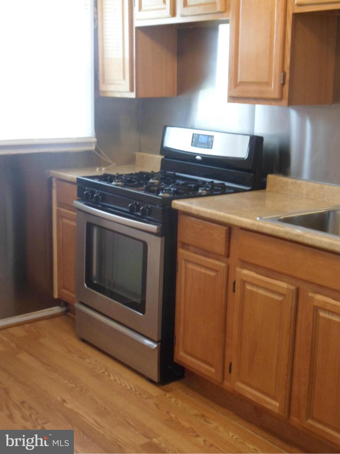 1333 Stonewood Road Baltimore, MD 21239 - Photo 13 of 30 a kitchen with granite countertop cabinets stainless steel appliances and wooden floor