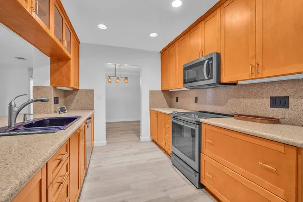 a kitchen with stainless steel appliances granite countertop a sink and cabinets with wooden floor