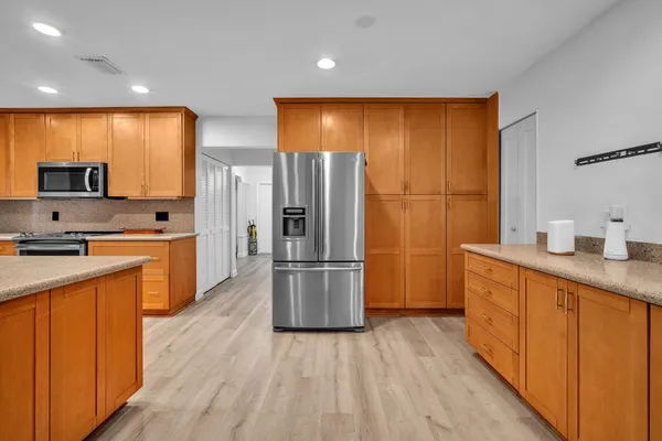 a kitchen with stainless steel appliances a refrigerator and wooden floor