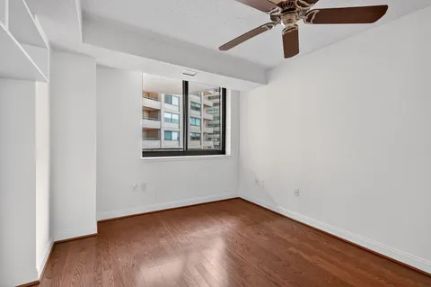 a view of an empty room with window and wooden floor