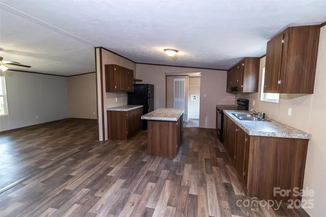 a kitchen with granite countertop wooden cabinets a stove a sink and dishwasher with wooden floor