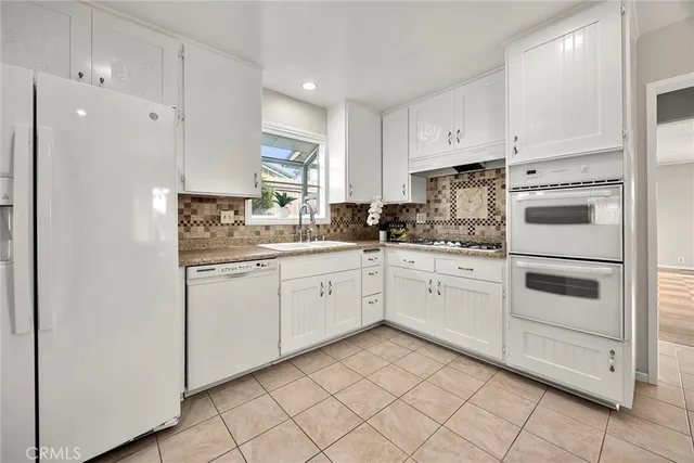 a kitchen with white cabinets appliances and a sink