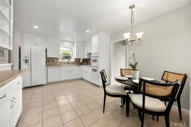 a kitchen with stainless steel appliances kitchen island granite countertop a dining table chairs and white cabinets