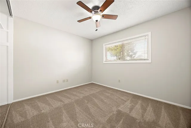 an empty room with a window and a ceiling fan