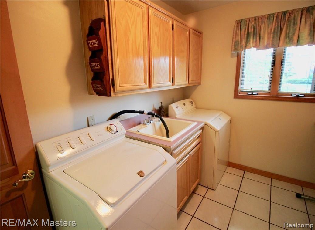 26454 Rinne Road New Boston, MI 48164 - Photo 23 of 41 Laundry room off the kitchen area has its own sink, cabinets for storage, and room for ironing board, and folding table...easy to keep clean with tile floors.