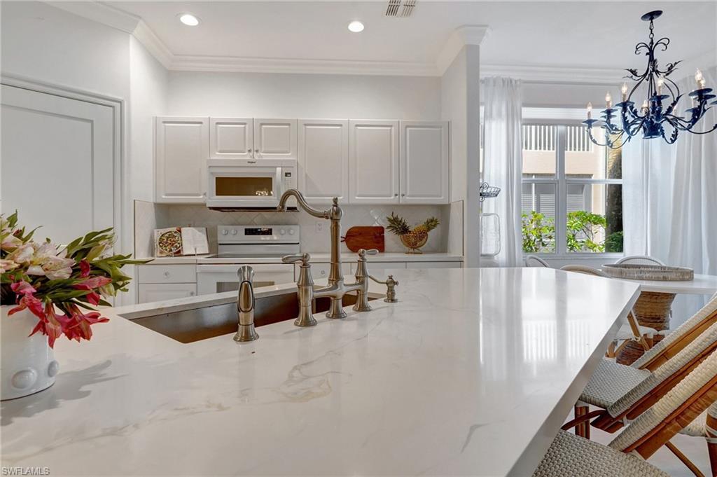 889 Carrick Bend Circle, Unit 1701 Naples, FL 34110 - Photo 11 of 32 a kitchen with granite countertop a refrigerator and a stove top oven