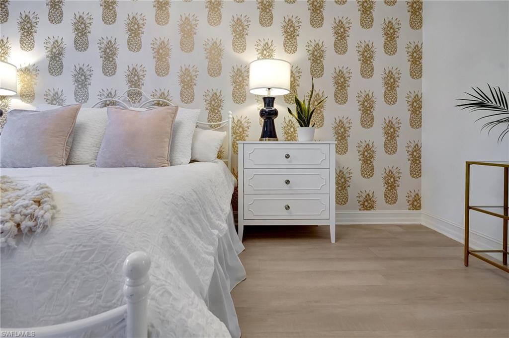 889 Carrick Bend Circle, Unit 1701 Naples, FL 34110 - Photo 24 of 32 a spacious bedroom with a bed and a lamp on a dresser