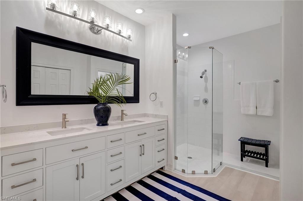 889 Carrick Bend Circle, Unit 1701 Naples, FL 34110 - Photo 26 of 32 a bathroom with double vanity sink a mirror and a shower