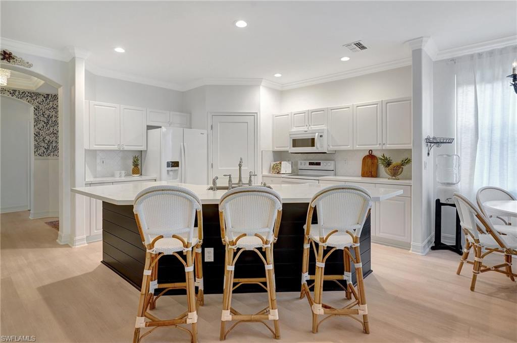 889 Carrick Bend Circle, Unit 1701 Naples, FL 34110 - Photo 5 of 32 a kitchen with stainless steel appliances kitchen island granite countertop a dining table chairs and white cabinets
