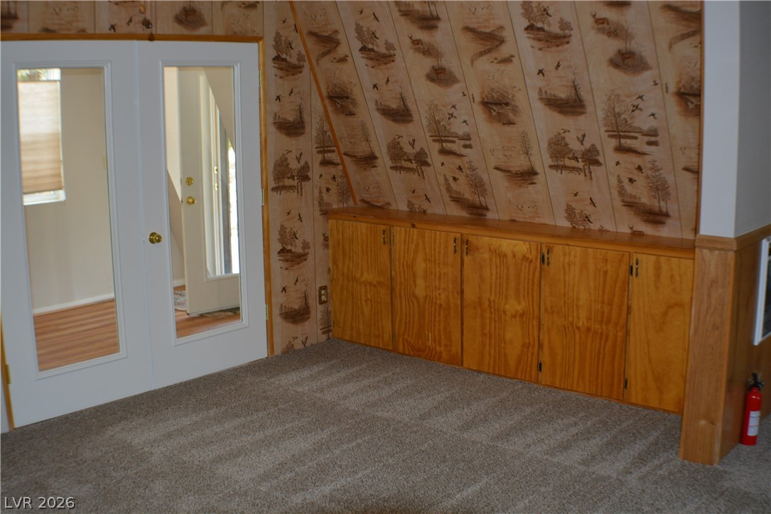 1321 Trout Canyon Road Las Vegas, NV 89124 - Photo 19 of 50 French doors open into a space featuring built-in cabinetry and a distinctive angled ceiling.