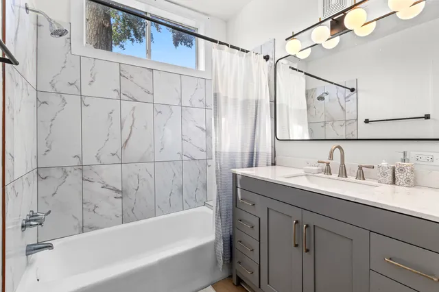 a bathroom with a granite countertop sink a mirror a shower and a bathtub