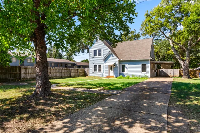 a front view of a house with a garden and trees