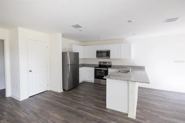 a kitchen with a refrigerator stove and wooden floor