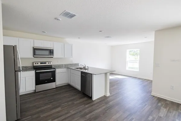 a kitchen with granite countertop a refrigerator and a stove top oven