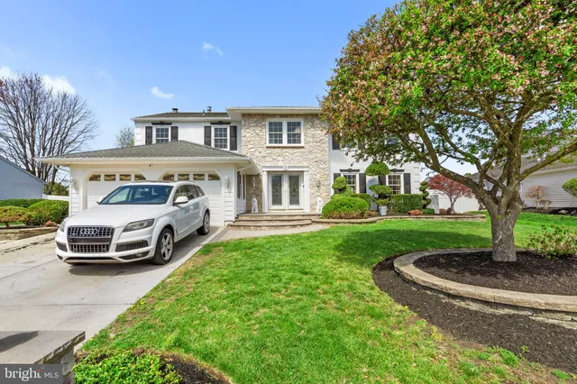 a front view of a house with a garden and trees