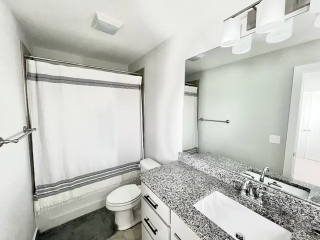 a bathroom with a granite countertop sink toilet and shower