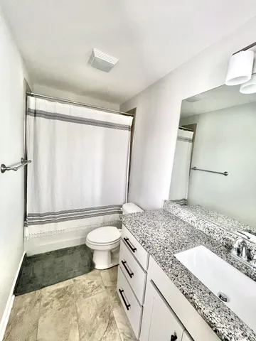 a bathroom with a granite countertop sink toilet and shower