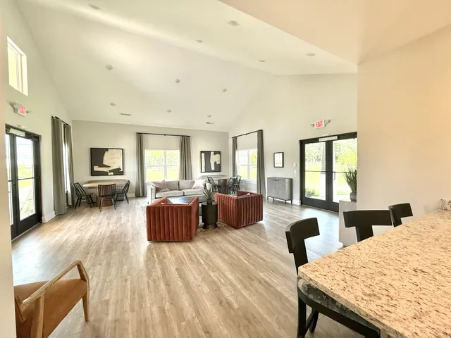a living room with furniture kitchen view and a large window