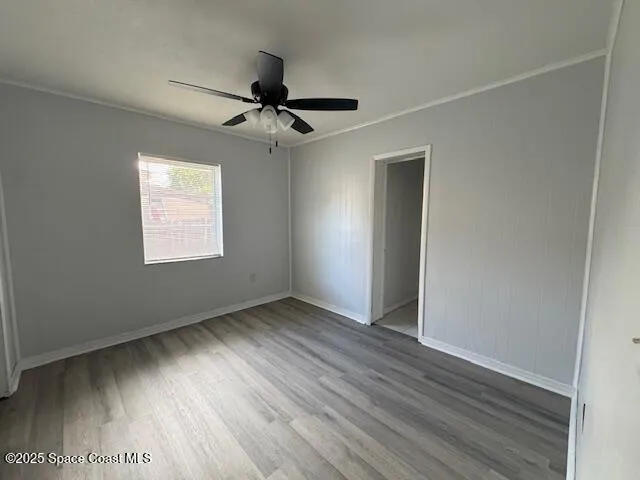 an empty room with wooden floor closet and windows