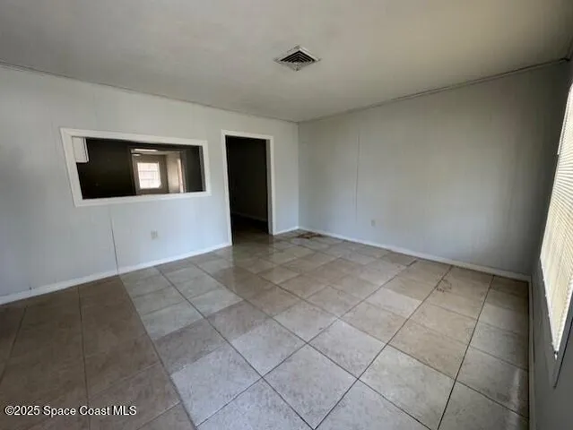 an empty room with wooden floor chandelier fan and windows