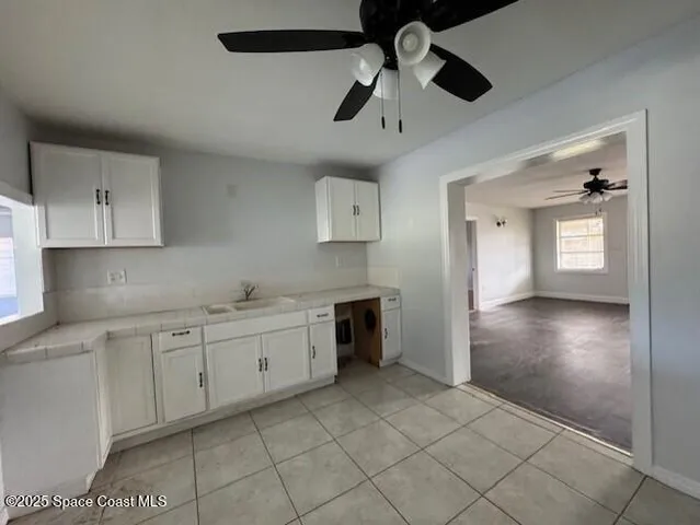 an empty room with wooden floor chandelier fan and windows