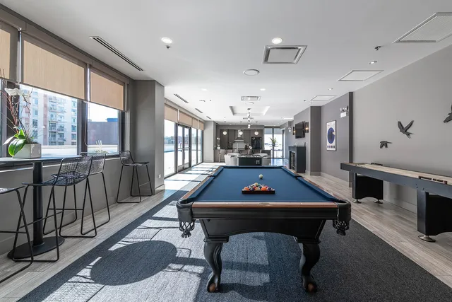 a room with furniture pool table flat screen tv and windows