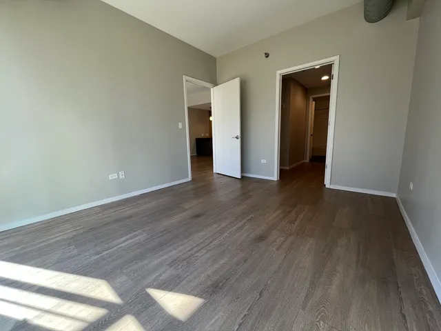 a view of an empty room with wooden floor and closet