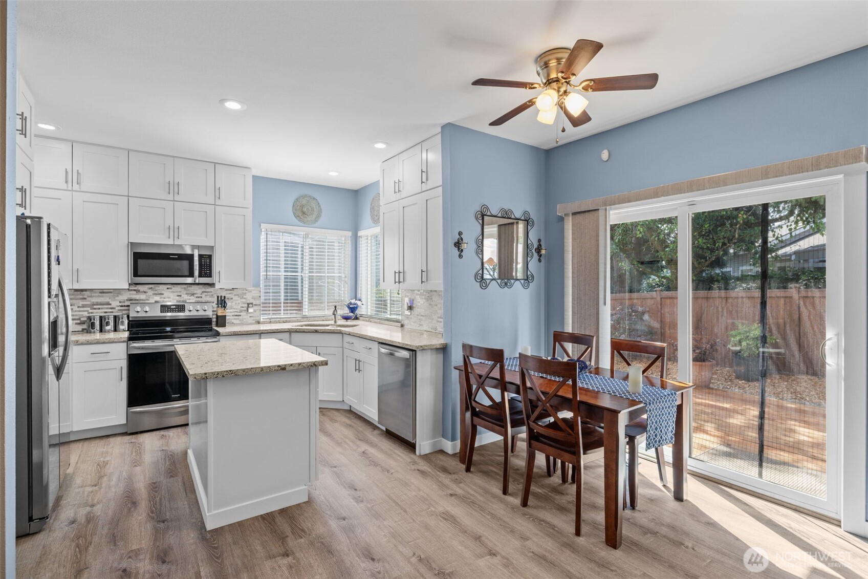 5021 South 232nd Street, Unit 75 Kent, WA 98032 - Photo 12 of 40 a kitchen with stainless steel appliances kitchen island granite countertop a stove a refrigerator a sink a dining table and chairs with wooden floor