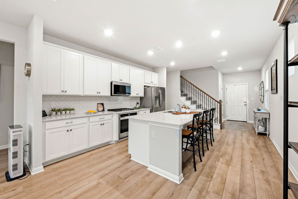 2417 Roosevelt Road Leander, TX 78641 - Photo 11 of 40 Kitchen featuring an island with sink, a kitchen bar, white cabinetry, appliances with stainless steel finishes, and recessed lighting