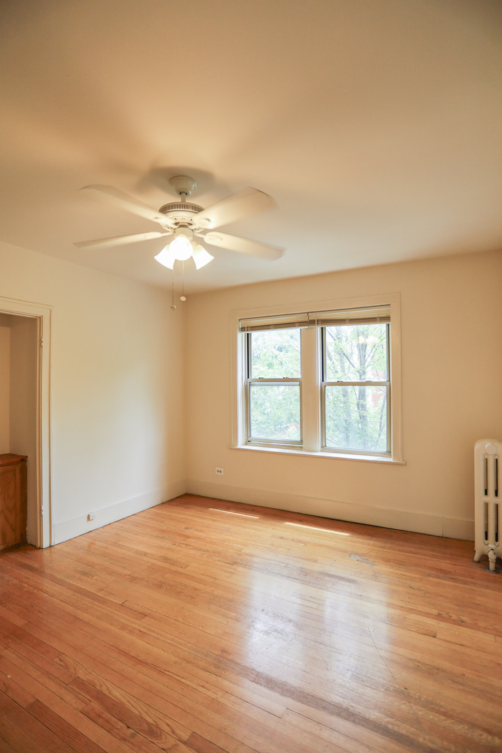 1100 West Roscoe Street, Unit 13 Chicago, IL 60657 - Photo 4 of 9 an empty room with wooden floor and windows