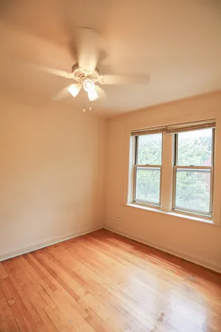 an empty room with chandelier fan and windows