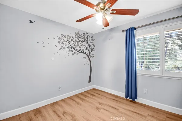 an empty room with wooden floor fan and windows