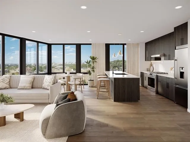 a living room with furniture potted plant kitchen view and large windows