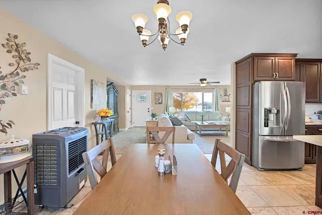 a living room with furniture a chandelier and a refrigerator