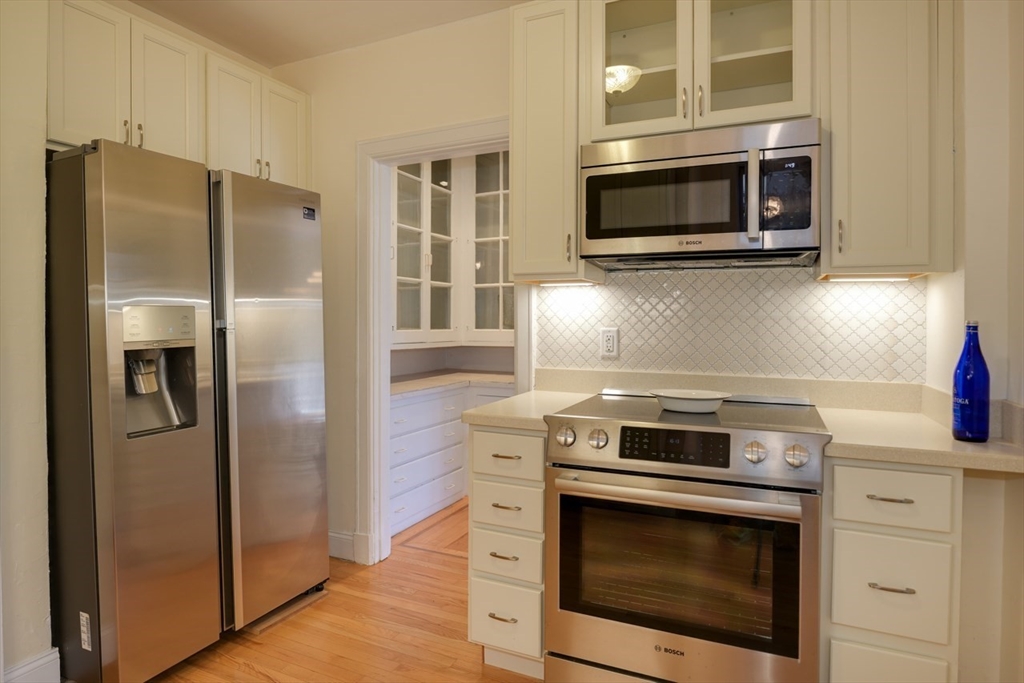 983 Memorial Drive, Unit 502 Cambridge, MA 02138 - Photo 9 of 33 a kitchen with stainless steel appliances wooden floor sink and wooden cabinets