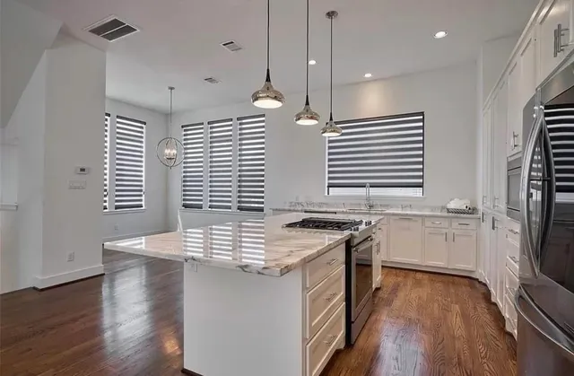 a kitchen with stainless steel appliances granite countertop a stove a sink dishwasher and a refrigerator with wooden floor